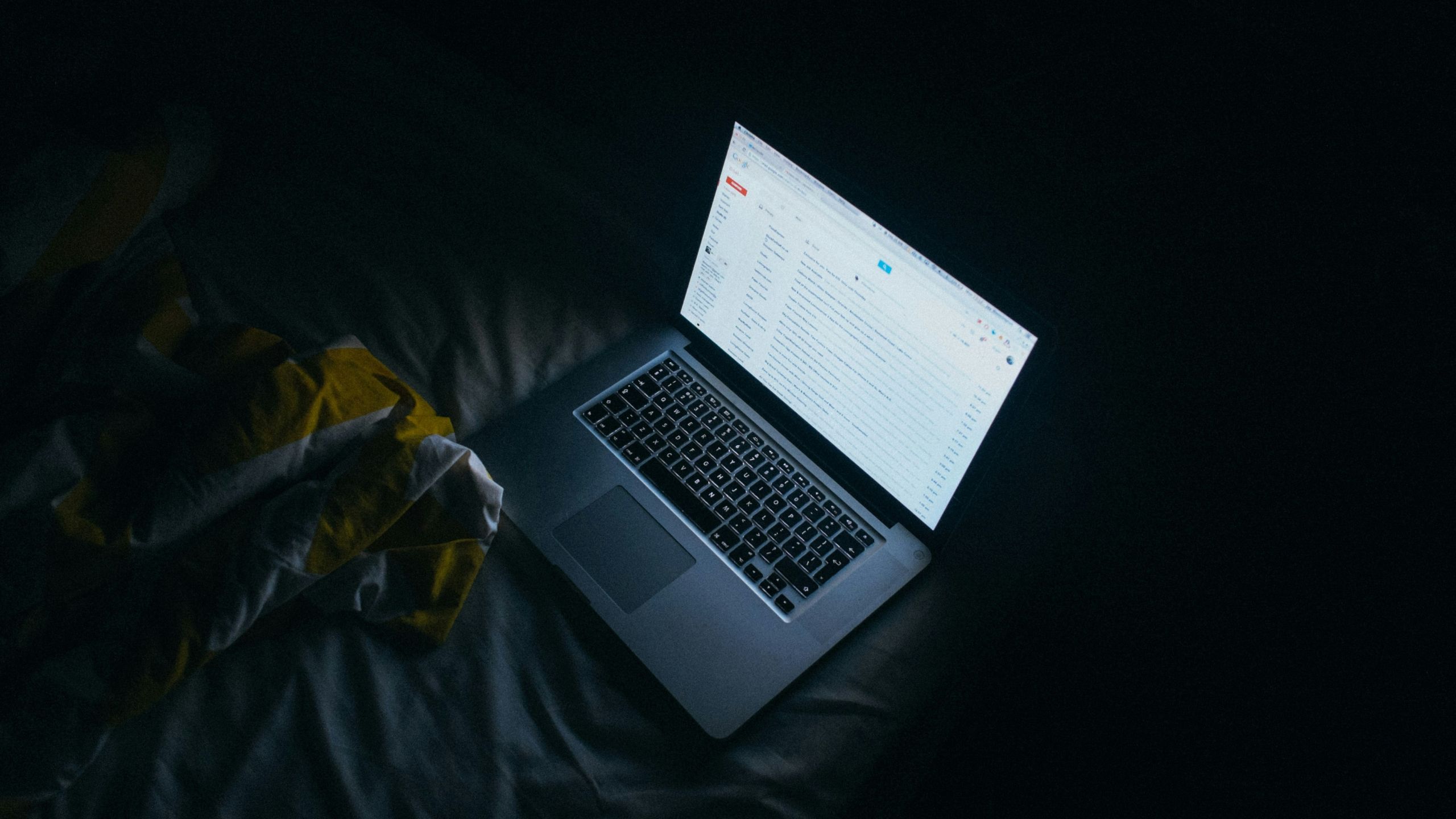 A computer with Gmail pulled up in a dark room. 