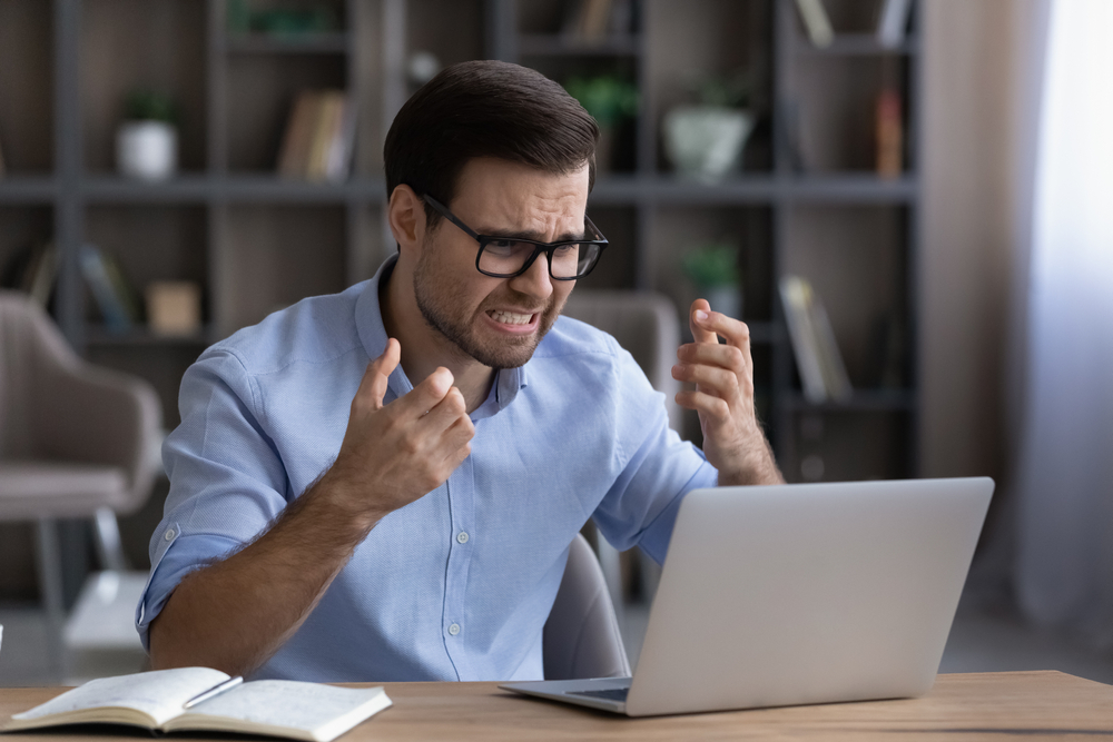 Person using a laptop and looking angry