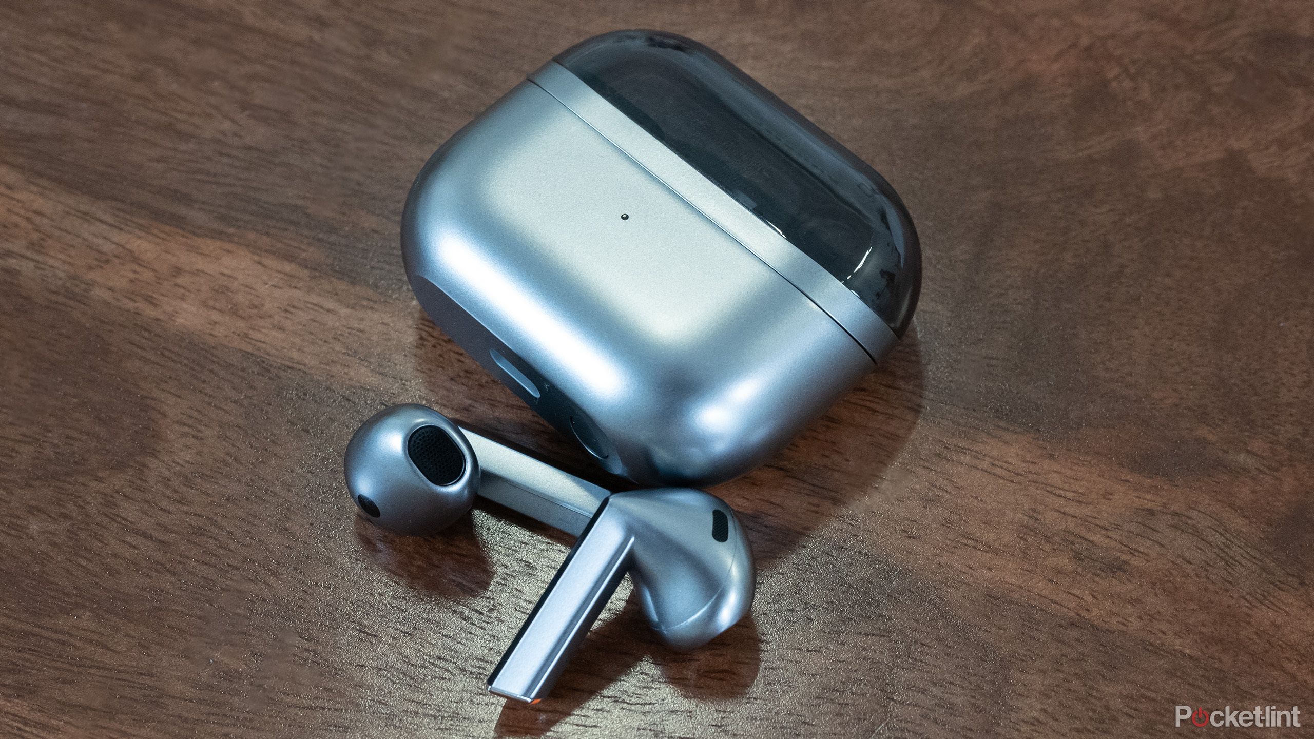 The Samsungn Galaxy Buds 3 earbuds and case resting on a wooden surface.