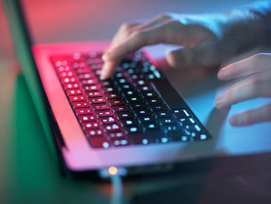 Hacker working on illuminated laptop at office