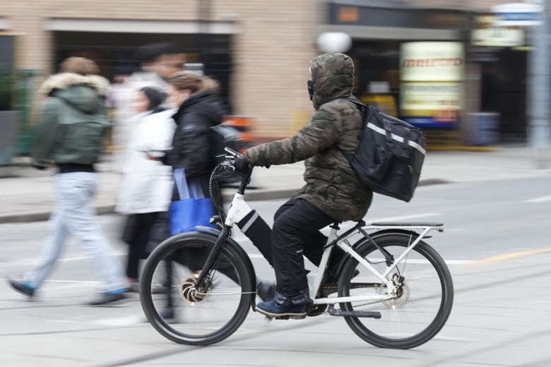 A food-delivery courier drives an e-bike in Toronto in January 2024.