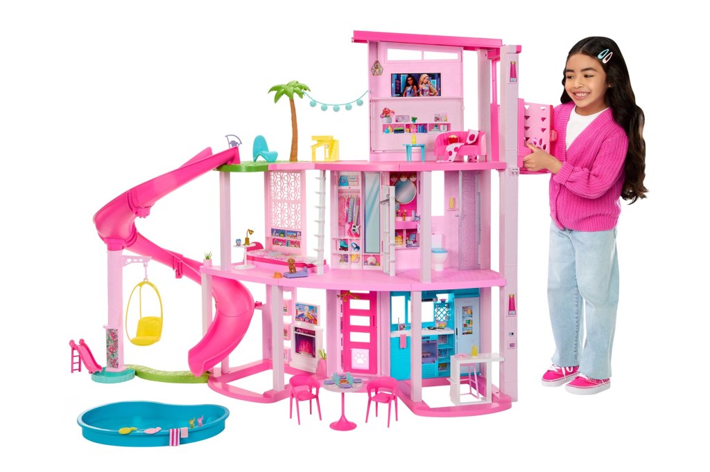 Aubrey Anderson-Emmons standing next to a Barbie Dreamhouse with a pool party setup