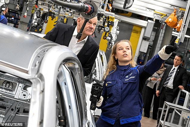 Mr Scholz, seen here visiting a BMW plant in Munich in December last year, has called for the fines that would be levied to be spent by manufacturers on reducing emissions instead