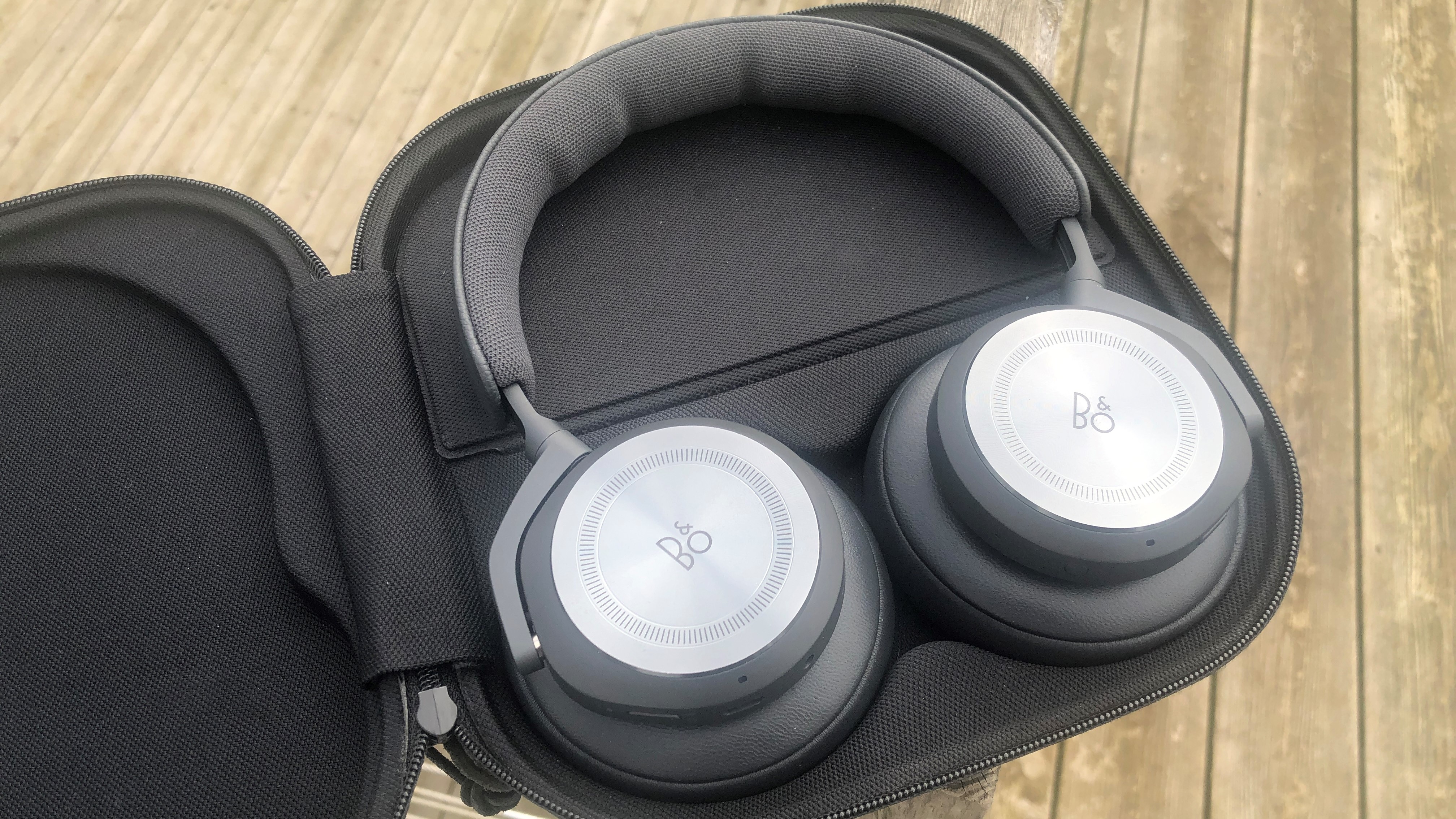 Bang & Olufsen Beoplay HX headphones in an open case on picnic bench