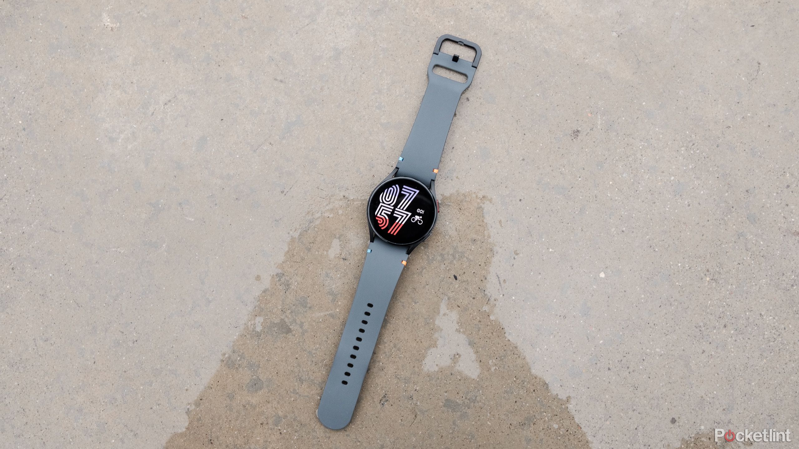 A black Samsung Galaxy Watch FE sits on a pool of water