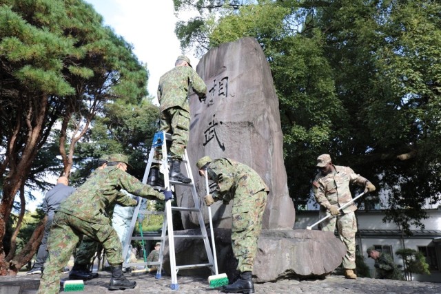 765th Transportation (Terminal) Bn. Soldiers, Japan Ground Self-Defense Force members work together to beautify historical stone monument on Camp Zama