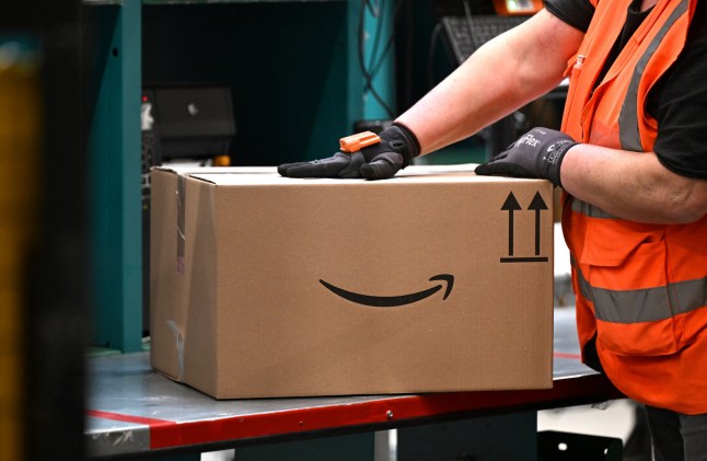 A worker moves a package with the logo of Amazon at a packing station of a redistribution centre of US online retail giant Amazon in Werne, western Germany, on November 21, 2024. (Photo by Ina FASSBENDER / AFP) (Photo by INA FASSBENDER/AFP via Getty Images)