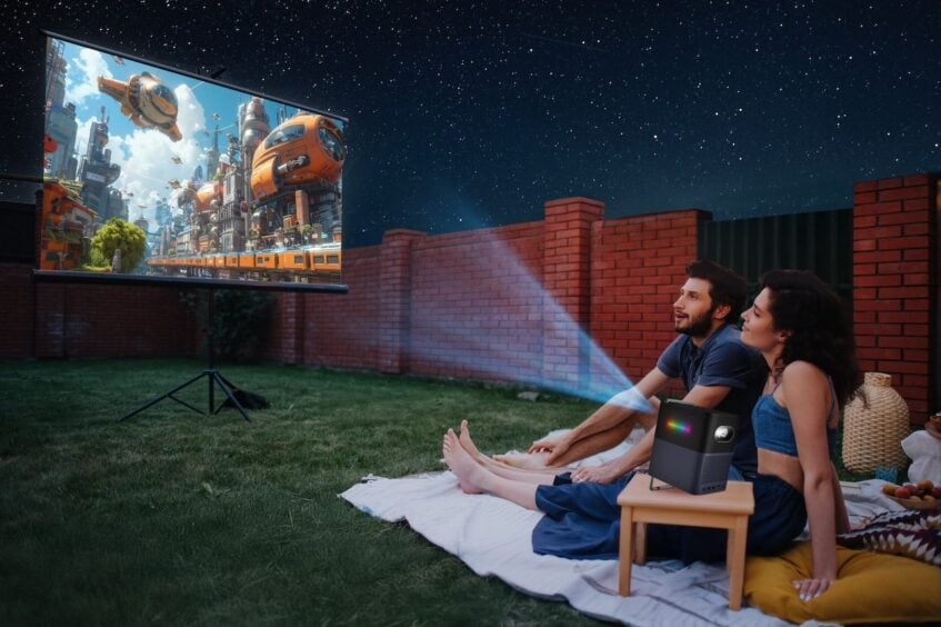 Man and woman seated on blanket watching a projected movie