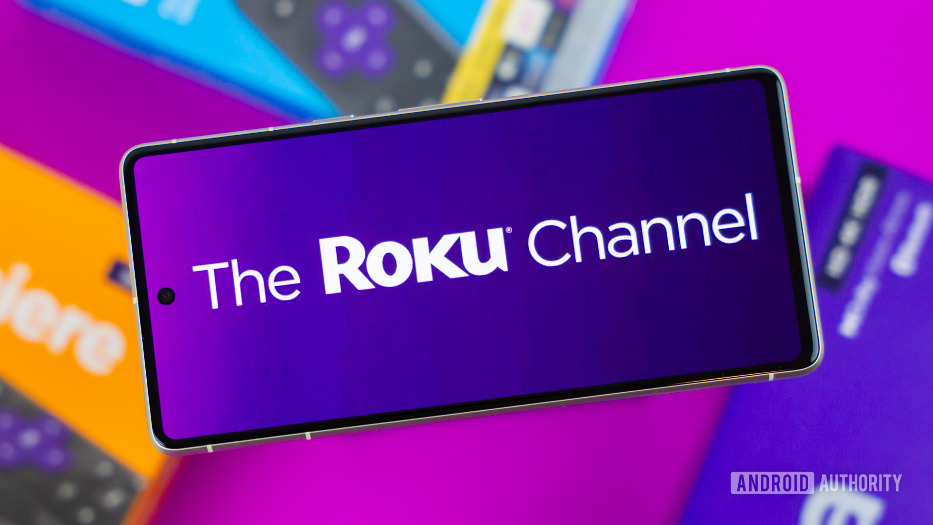 Stock photo of The Roku Channel logo on phone next to Roku boxes 2