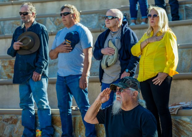 Veterans and others in attendance stand for the national anthem...