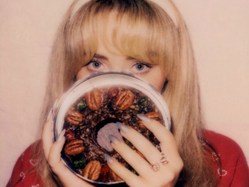 Sabrina Carpenter covering her face with fruitcake designed disc