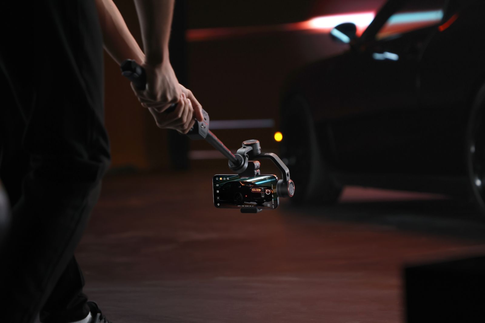 Someone filming a car using the Hohem iSteady M7 s extension rod