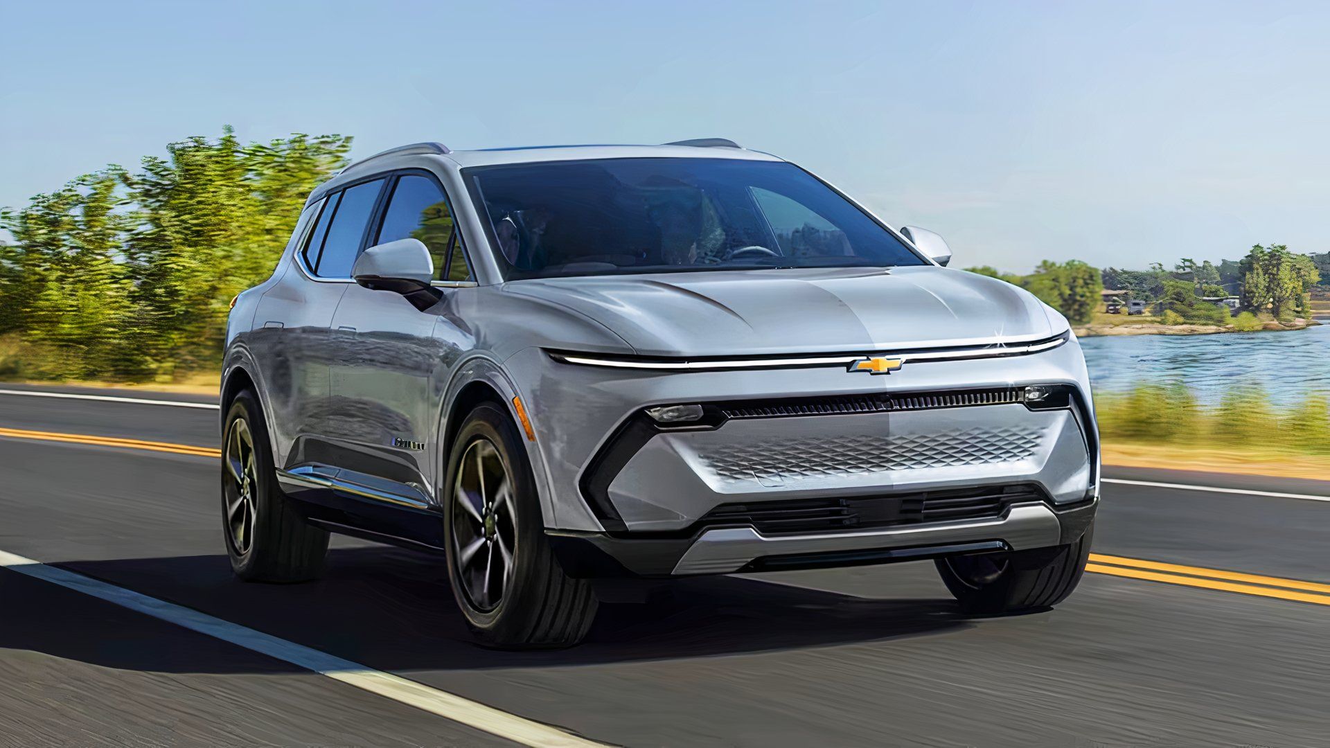 A gray 2025 Chevrolet Equinox EV midsize electric SUV is driving on the road. 