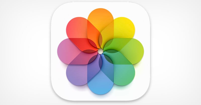 A colorful, abstract flower-like design with overlapping petals in shades of red, orange, yellow, green, blue, and purple, set against a white background within a rounded square.