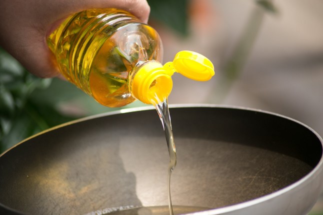 Pouring food oil in hot pan for deep frying.