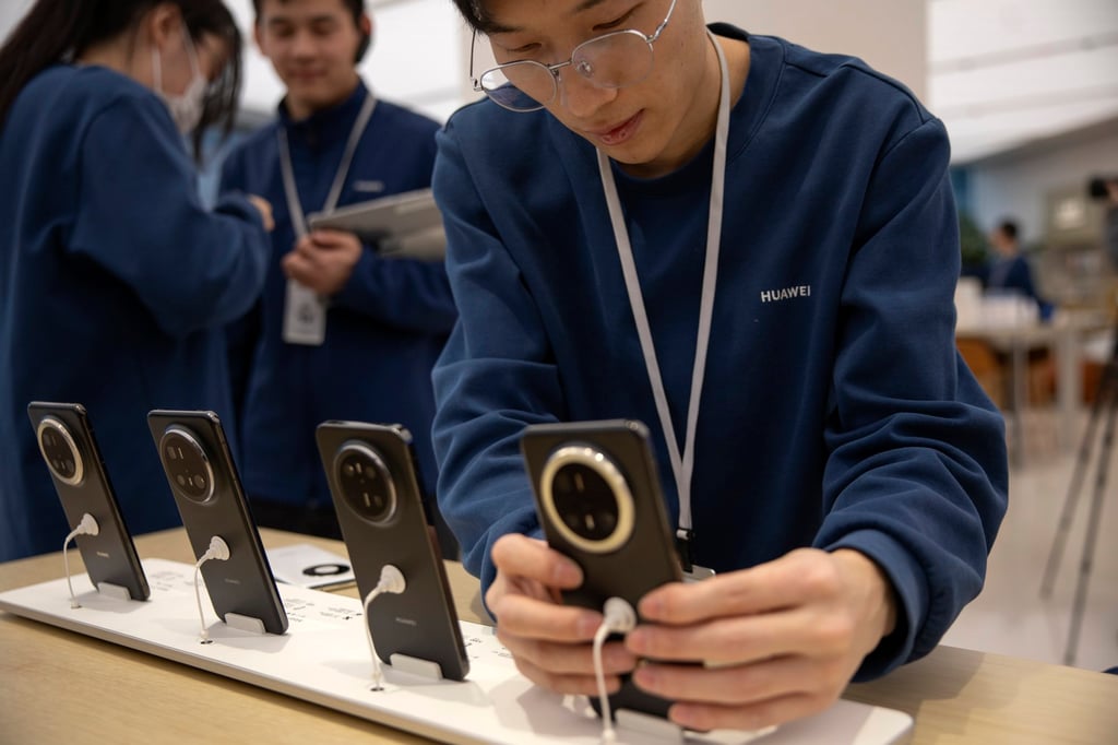 A Huawei Technologies sales staff arranges the new Mate 70 series display at the company’s store in Beijing on November 26, 2024. Photo: EPA-EFE