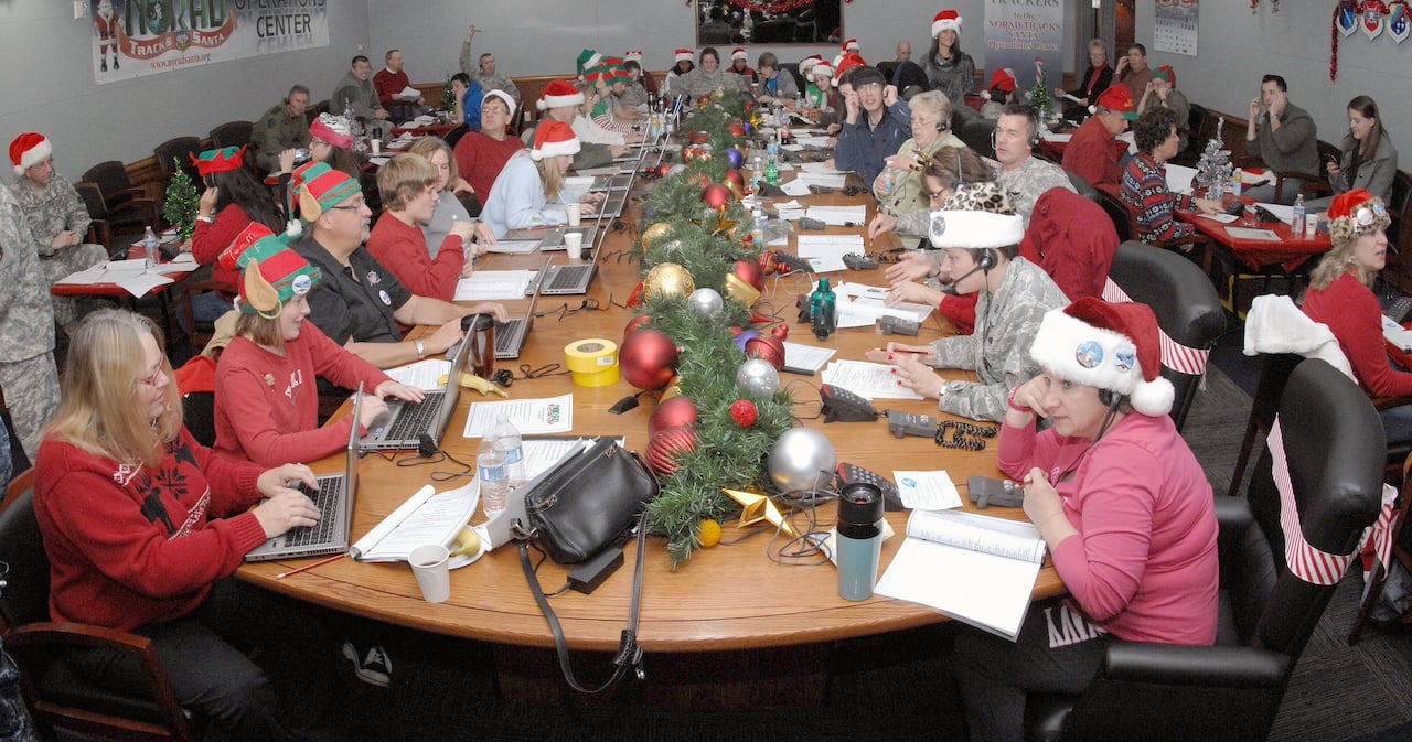 NORAD staff seated around long table wearing Christmas hats