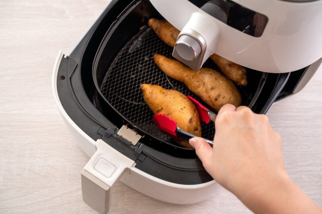 This is a photo of a woman cooking sweet potatoes in an air fryer. See PA Feature FINANCE Bills. WARNING: This picture must only be used to accompany PA feature FINANCE Bills. PA Photo. Picture credit should read: Alamy/PA. NOTE TO EDITORS: This picture must only be used to accompany PA Feature FINANCE Bills.