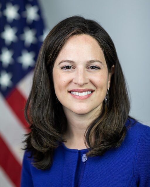 Anne Neuberger in blue shirt smiling at camera