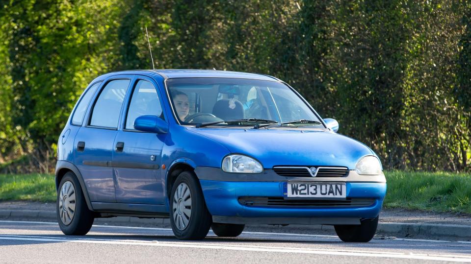 Blue Vauxhall Corsa driving on a road.