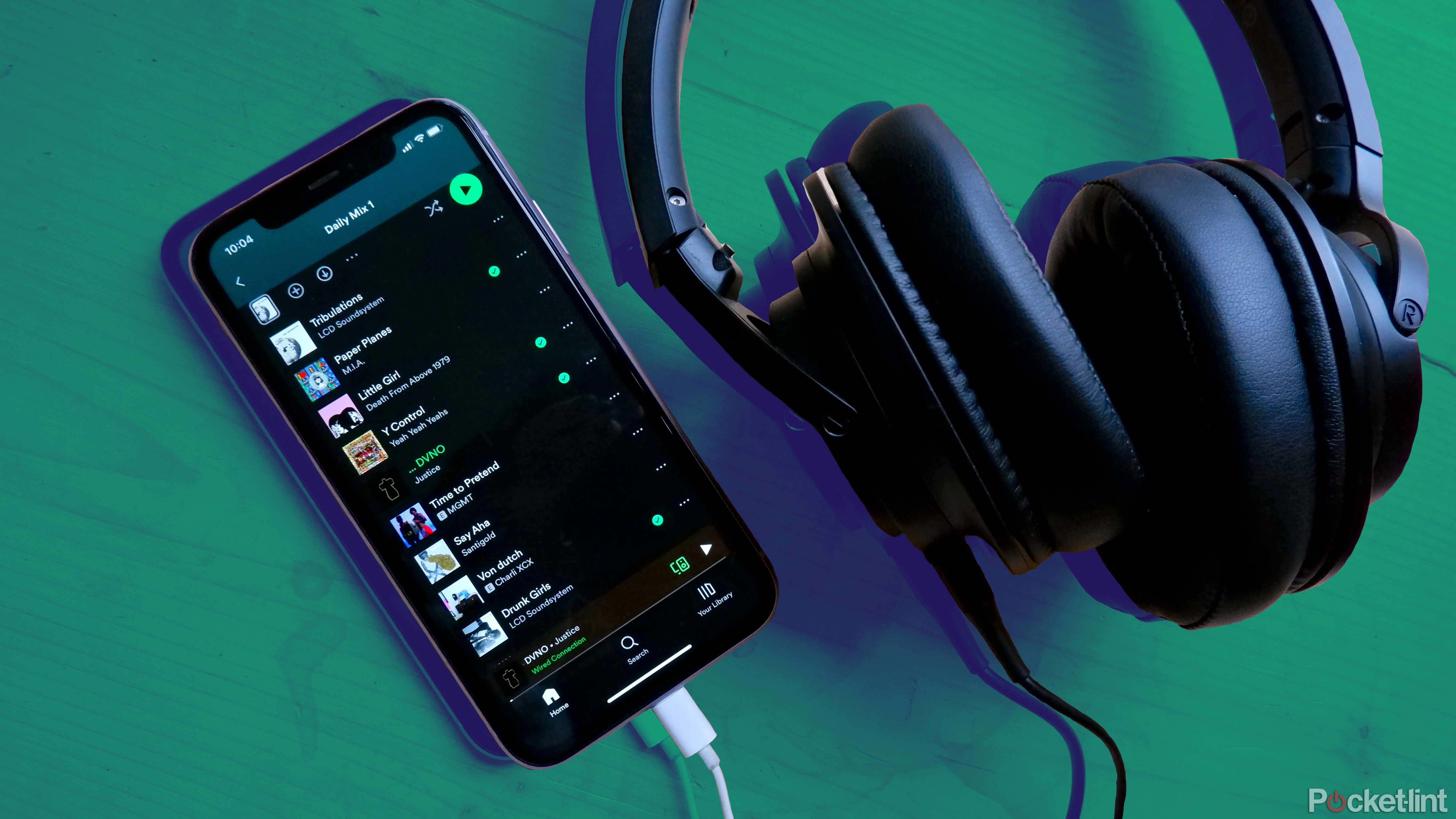 An iPhone with Spotify open with a pair of headphones plugged in