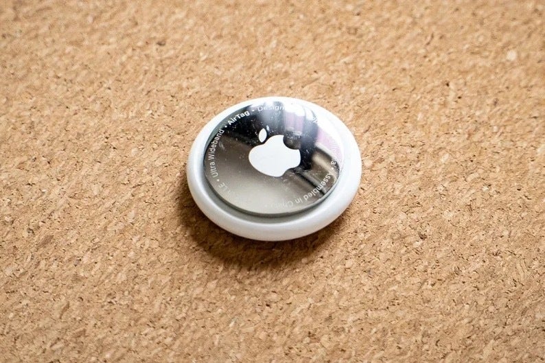 An image of an Apple Airtag on a corkboard surface