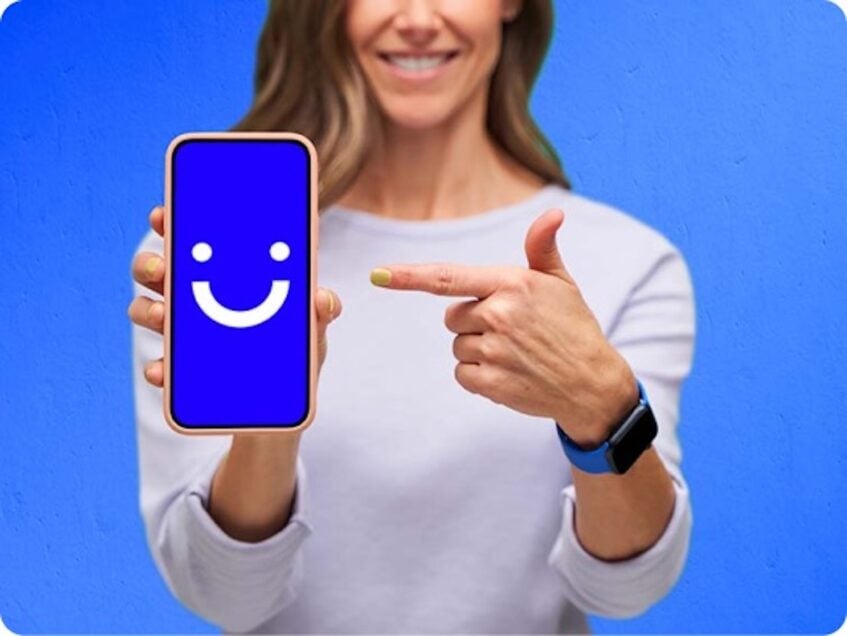 Woman holding phone displaying Visible logo and point at it with other hand