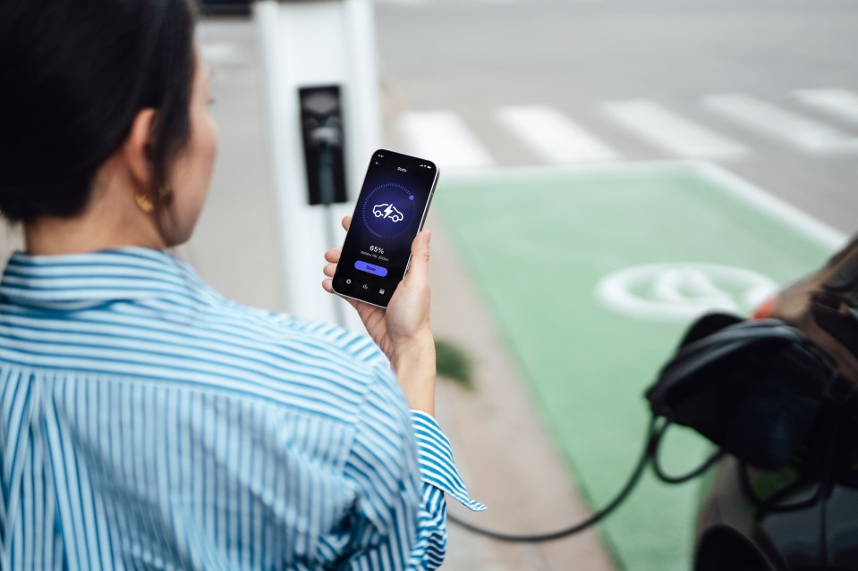 Woman using a phone app to monitor her electric car charging.