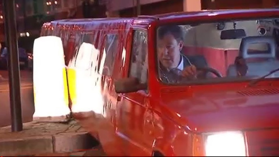 Man driving a red car at night.