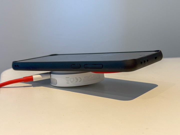 The OnePlus 50W AirVOOC charger attached to a OnePlus 13 lying flat on a desk