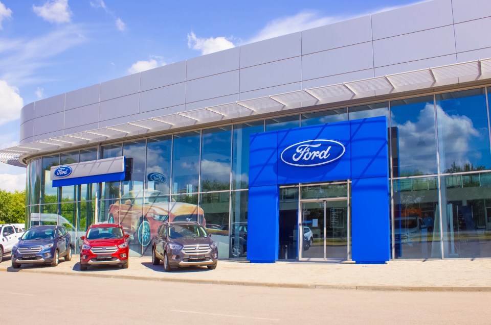 Ford dealership with cars parked in front.