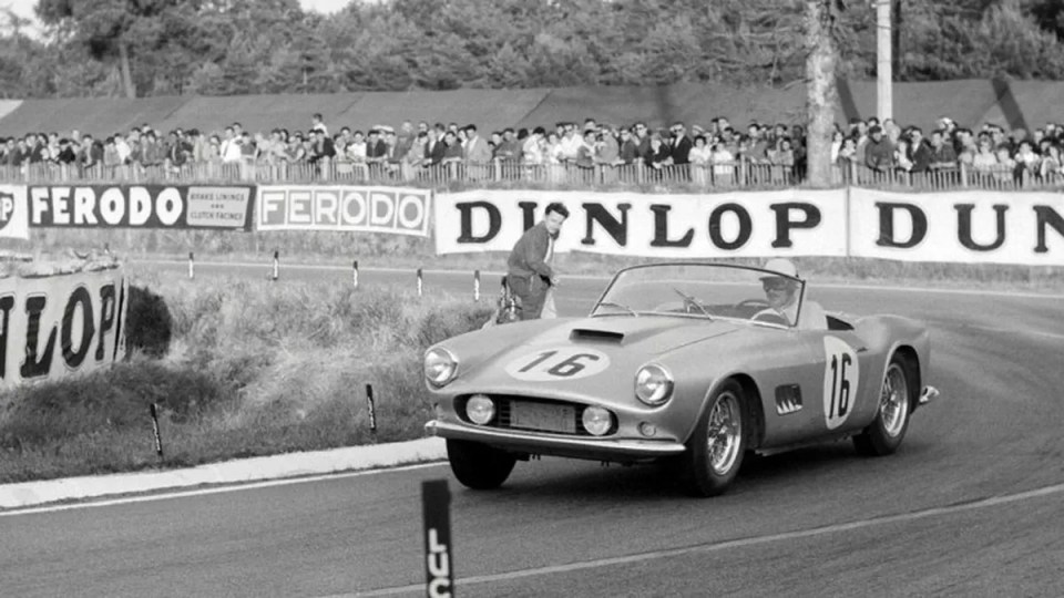 Black and white photo of a silver Ferrari 250 GT California Spider racing at Le Mans.