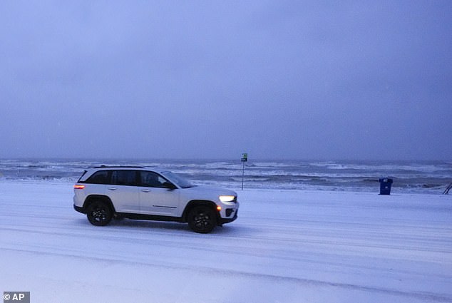 An SUV drives along a snow-covered road in Galveston, TX in the early morning hours of January 21, 2025