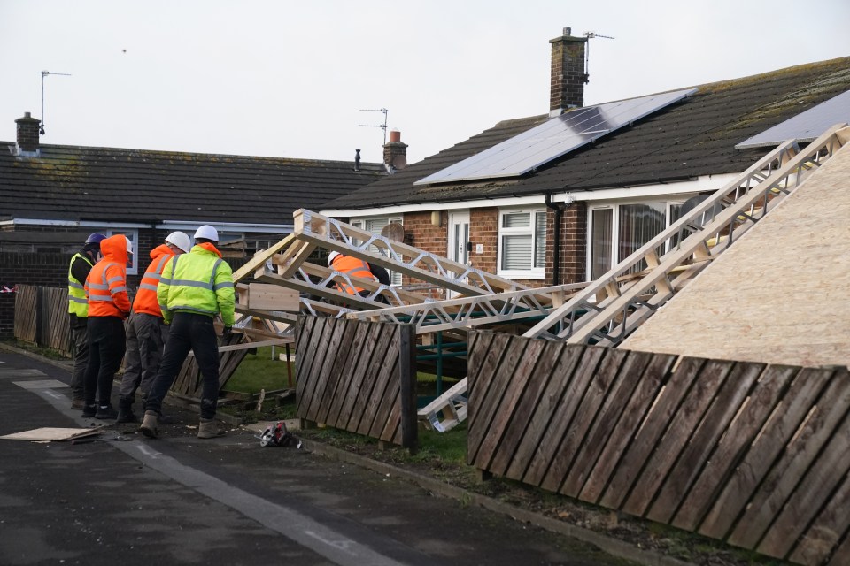 Workers surveying roof damage after strong winds.