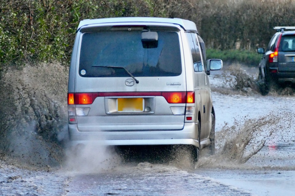 Vehicles driving through floodwater on a road.