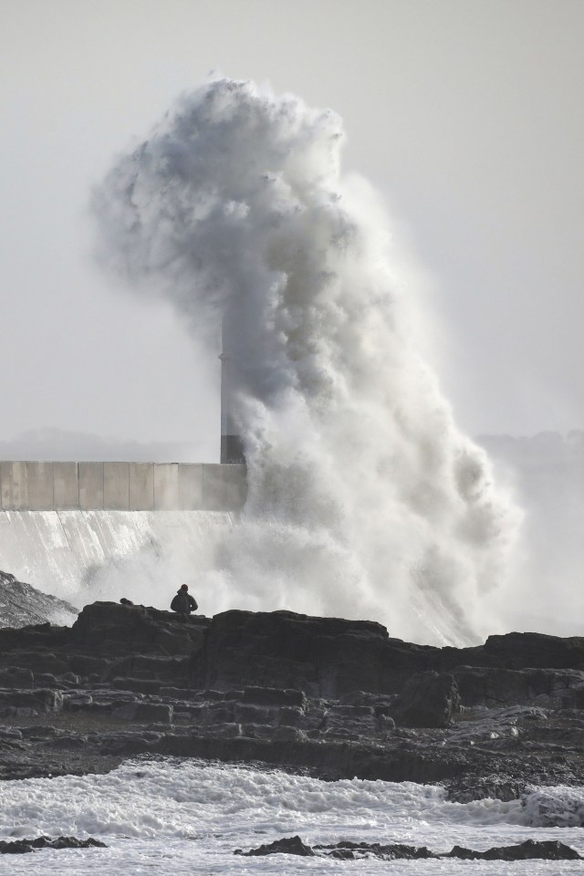 Waves crashing against a lighthouse and breakwater in Porthcawl, Wales.