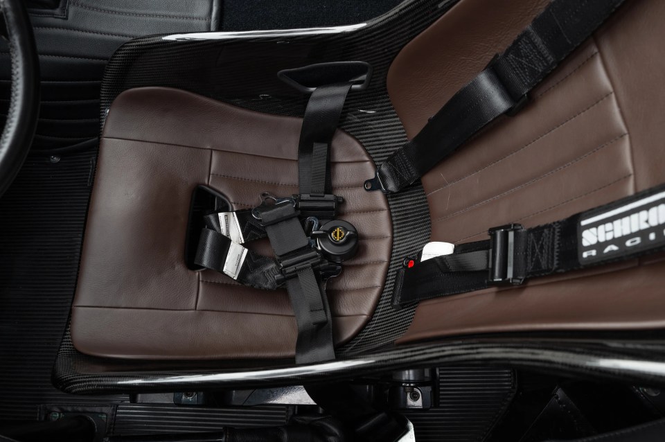 Brown leather and carbon fiber racing seat with five-point harness.