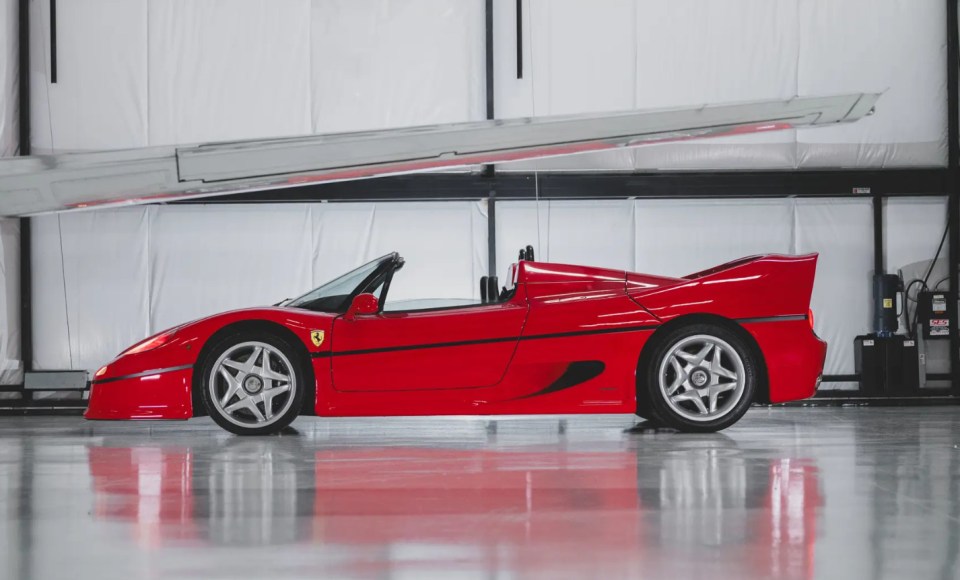 Red Ferrari F50 convertible in a garage.