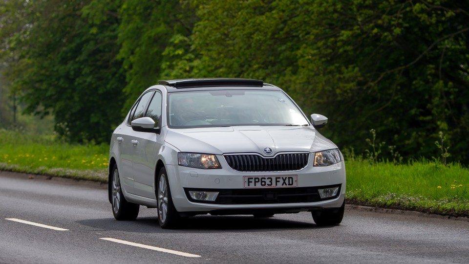 White Skoda Octavia driving on a road.