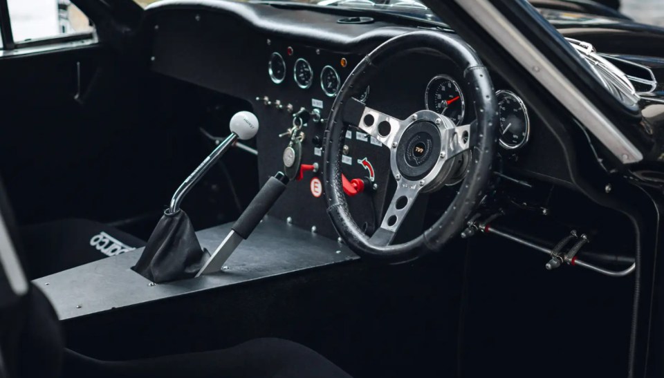 Interior view of a classic car's dashboard and steering wheel.