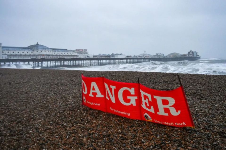 Danger sign on beach with rough seas, warning against swimming.