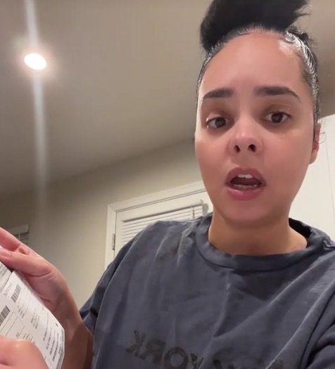 Woman holding a car registration renewal notice, expressing outrage at the $200 fee.