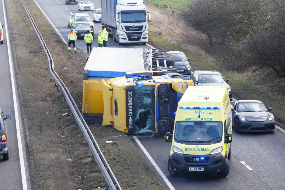 An overturned lorry and ambulance at a traffic accident scene.