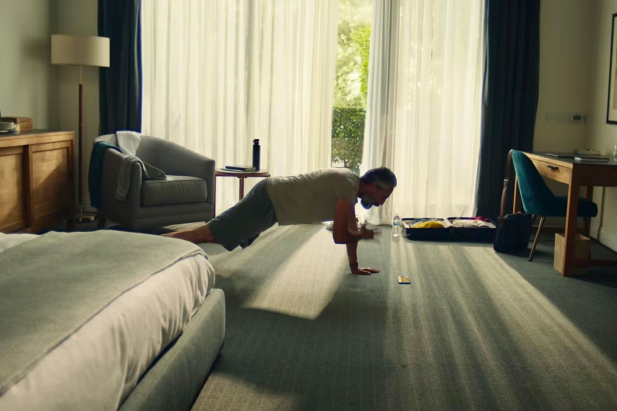 An individual doing a plank and working out at home while watching the instructor from their iPhone.