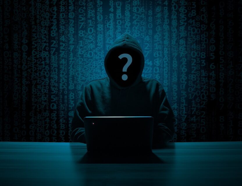 Hooded hacker with question mark in face using laptop with codes running behind them