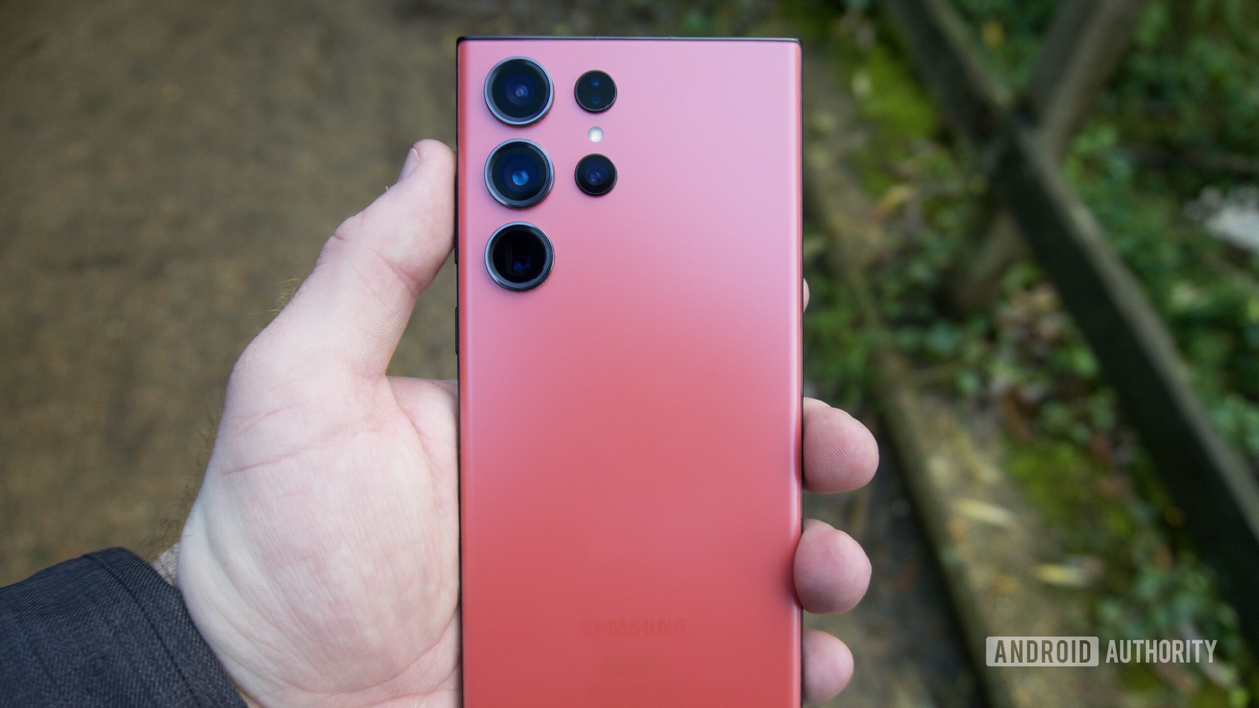 A red Galaxy S23 Ultra being held in-hand