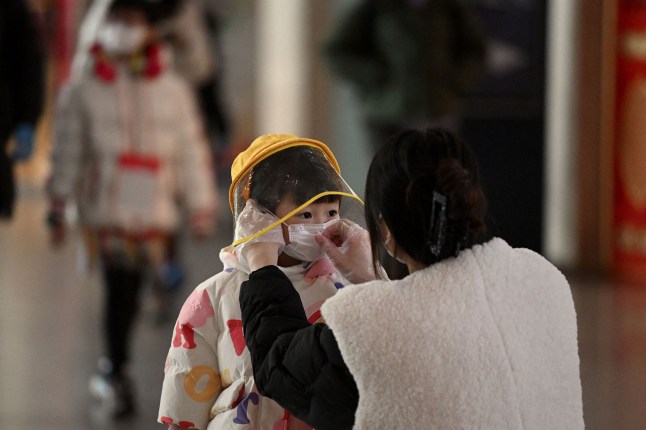 A woman arranges a face mask on a child's face