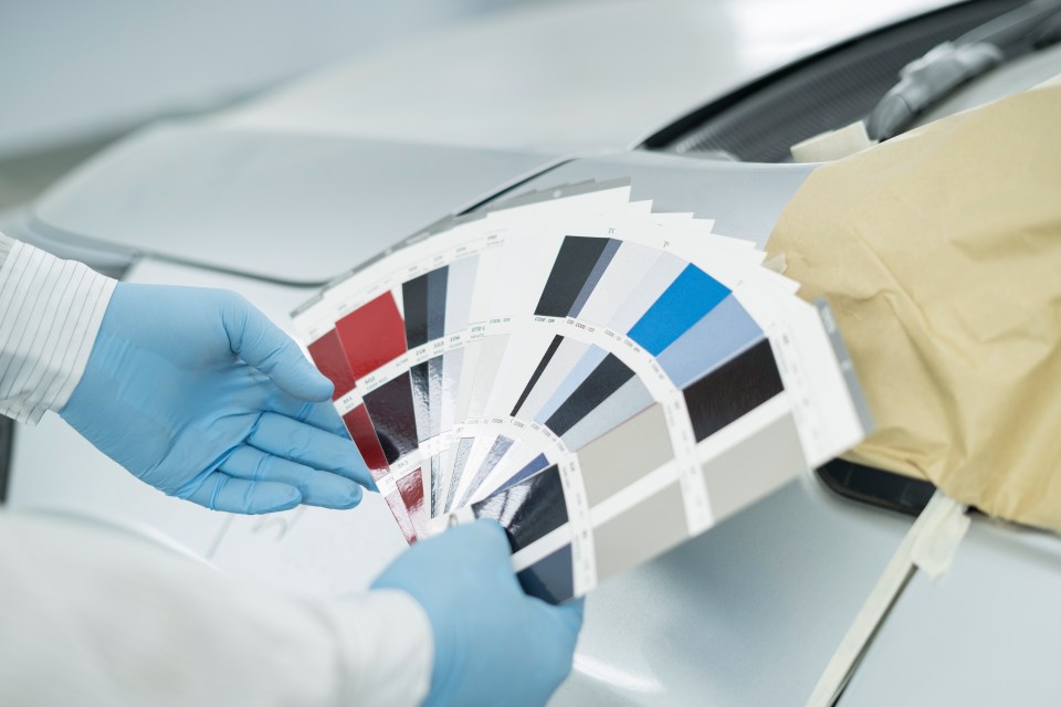 Technician matching car paint color using color samples.