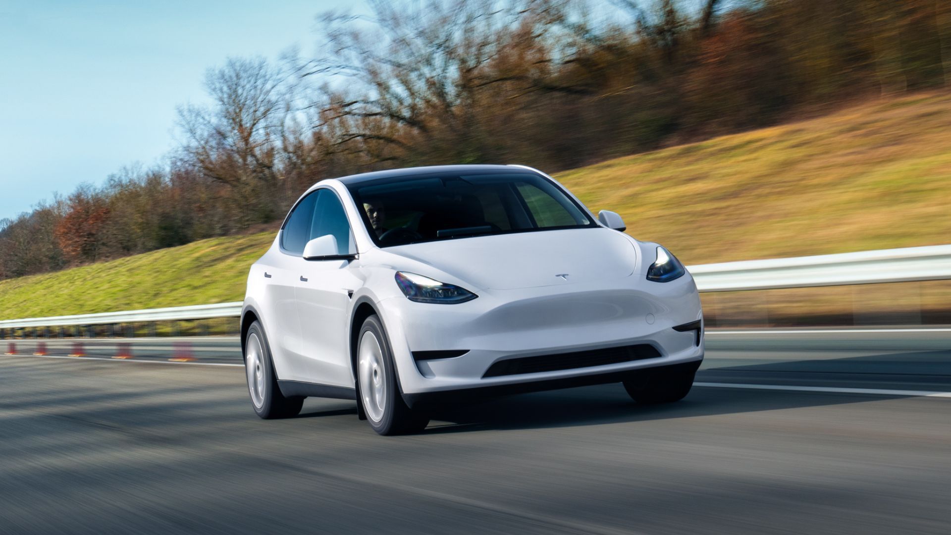 White Tesla Model Y driving on a freeway.