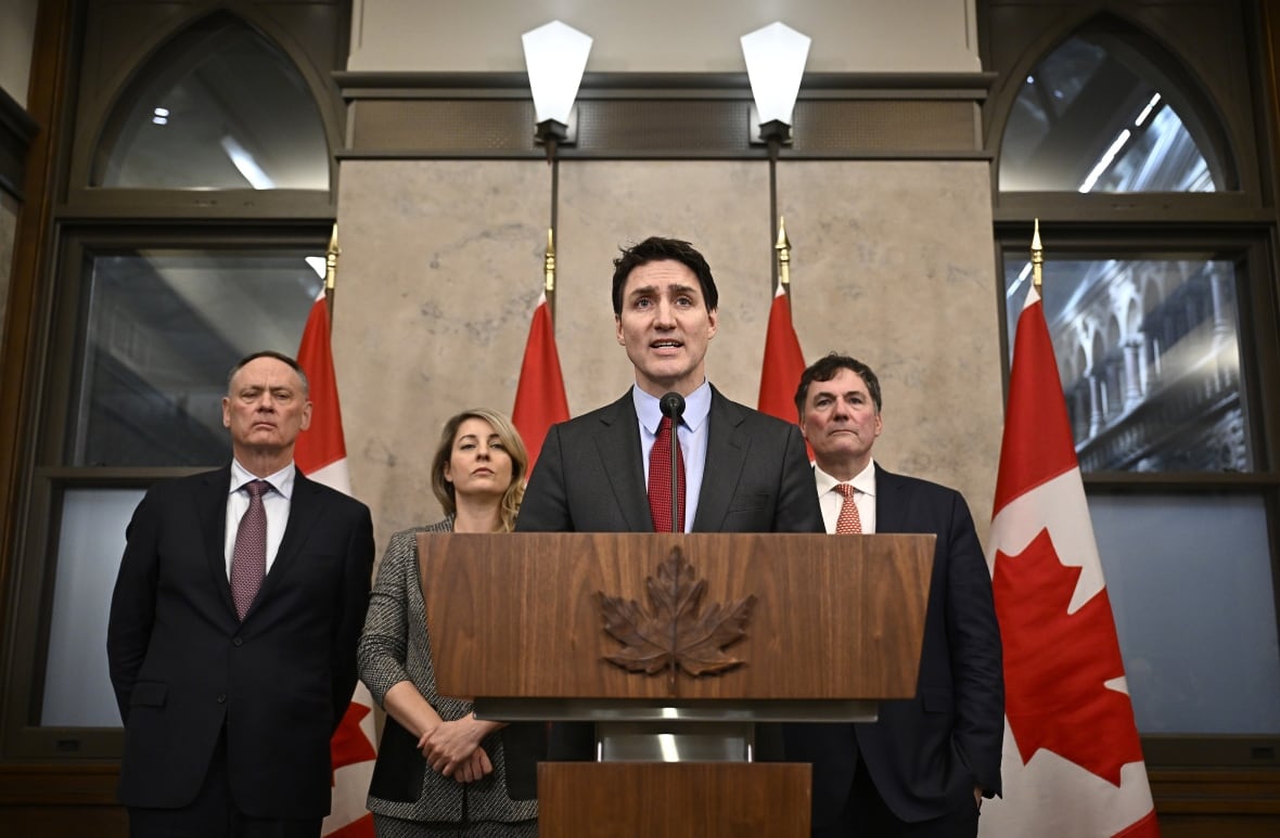 Trudeau and ministers stand behind a podium